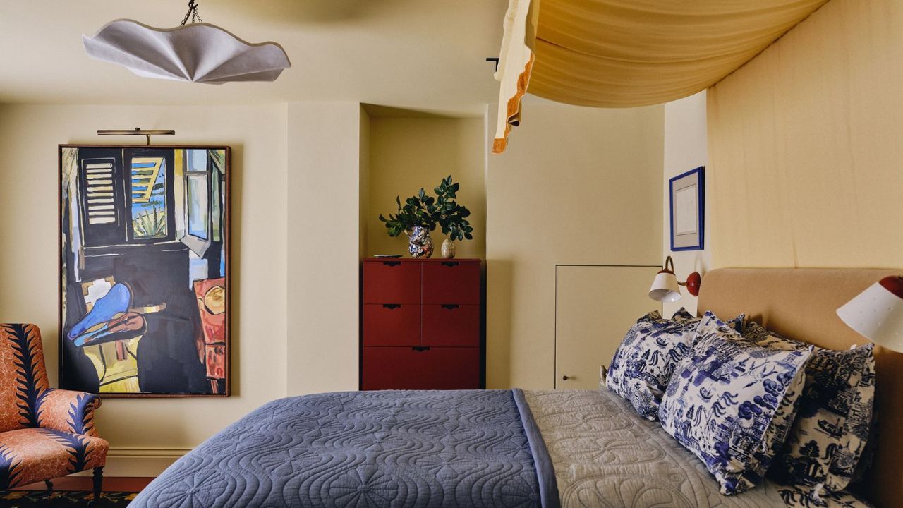 bedroom painted in butter yellow paint from the mylands x beata heuman collaboration with a yellow bed linen canopy and blue toile bedding 