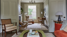 a traditional living room that leads into a study room with wooden furniture, rugs on the floor, floor lamps, accent chairs, and a ceiling light 